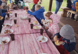 "Pszczółki" siedzą przy stole podczas degustacji kiełbaski.