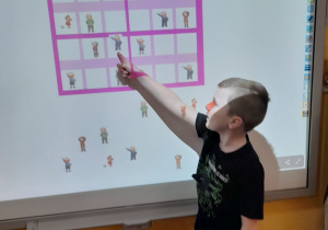 Mateusz układa na tablicy multimedialnej obrazkowe sudoku.