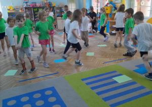 Dzieci poruszają się przy muzyce między kartkami leżącymi na podłodze.