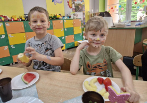 Franek i Olek siedzą przy stole zastawionym słodko-owocowymi potrawami.