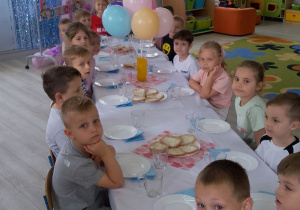 Dzieci siedzą przy wspólnym stole podczas świątecznego śniadania.