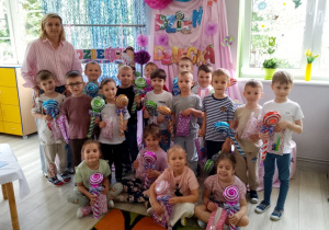 Zdjęcie grupowe na tle dekoracji z otrzymanymi upominkami i balonami.