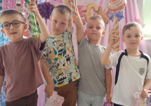Grupka chłopców pozują do zdjęcia na tle dekoracji z otrzymanymi upominkami.