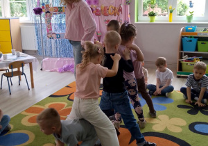 Przedszkolaki wraz z nauczycielem ustawione w ,,pociąg” podczas zabawy w „Węża”.