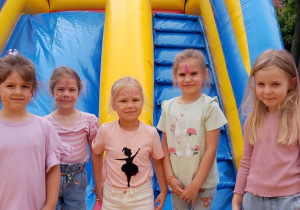 Grupka dziewczynek pozuje do zdjęcia na dmuchańcu.