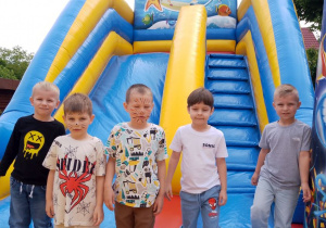 Pięciu chłopców pozuje do zdjęcia podczas zabawy na dmuchańcach.