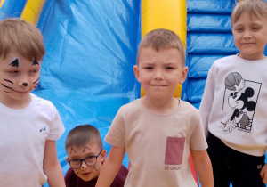 Grupka chłopców pozuje do zdjęcia na dmuchańcu.