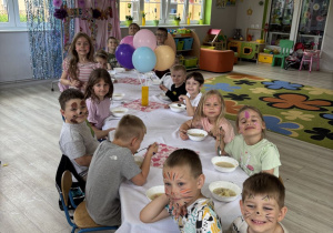 Dzieci siedzą przy stole, na którym podana jest zupka z obiadu.