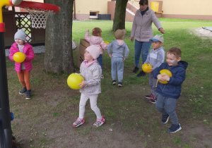 Grupka dzieci w trakcie zabawy z piłkami.
