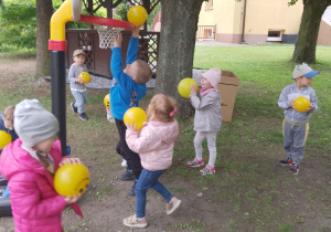 Grupka dzieci w trakcie zabawy z piłkami.