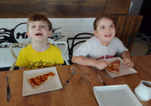 Antek i Lena przy stole degustują pizzę, którą chwilę wcześniej własnoręcznie przygotowywali.