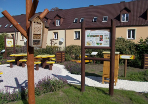 Część tematyczna "Z wizytą u pszczół": tablica dydaktyczna, ul dydaktyczny, stoły w kształcie plastra miodu, rzeźba pszczoły, kosz, domki dla owadów.