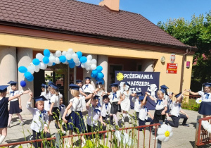 Dzieci tańczą walca na tarasie. Chłopcy klęczą na prawym kolanie, a dziewczynki obracają się wokół chłopców.