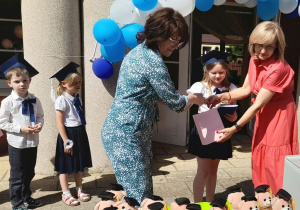 Pani dyrektor i Pani Lidka wręczają Julce dyplom i upominek.