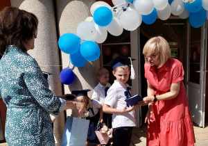 Pani dyrektor i Pani Lidka wręczają Antkowi dyplom i upominek.