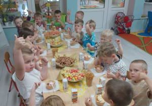 Dzieci pokazują uniesionym w górę kciukiem, że przygotowany poczęstunek bardzo im smakuje.