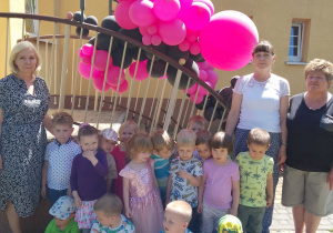 Grupa „Pszczółek” na tle balonów pozuje do wspólnego zdjęcia na powietrzu.