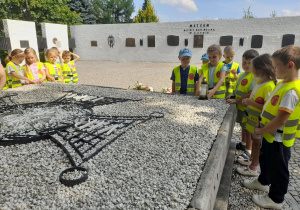 Dziewczynka stawia znicz na płycie upamiętniającej Żołnierzy Poległych w bitwie pod Kutnem. Obok stoją rówieśnicy.