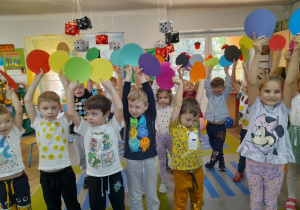 Dzieci podczas zabawy przy piosence "Kropka, kropeczka" podnoszą do góry kolorowe kółka (kropki).