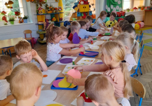 Dzieci siedzą przy wspólnym stole i tworzą kropkowe obrazki.
