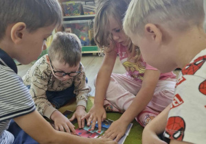 Wojtuś , Antoś, Weronika i Wojtuś układają kropkowy obrazek pocięty na części.