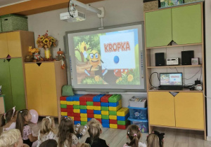 Dzieci oglądają film edukacyjny pt. "Karolek przedstawia Dzień Kropki".