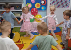 Przedszkolaki trzymają się za ręce tworząc duże koło.
