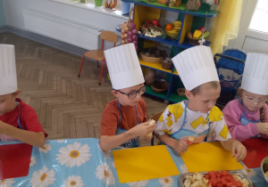 Przedszkolaki nadziewają na wykałaczki owoce.