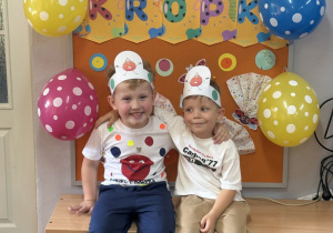 Olek i Wojtek pozują na tle gazetki z napisem Dzień Kropki.