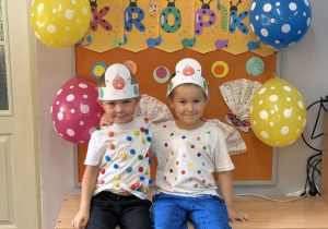 Filip i Tymon pozują na tle gazetki z napisem Dzień Kropki.