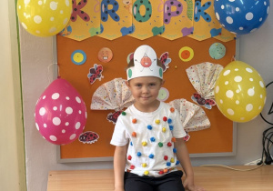 Filip pozuje na tle gazetki z napisem Dzień Kropki.