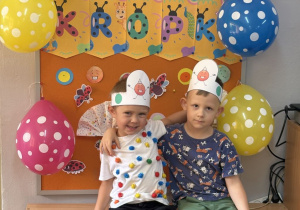 Filip i Piotrek pozują na tle gazetki z napisem Dzień Kropki.