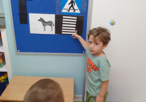 Michał wskazuje na tablicy ilustrację z przejściem dla pieszych.