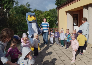 "Pszczółki" trzymają się za ręce i tańczą wspólnie z maskotką sowy.