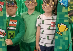 Julek, Antek i Fabian w Minecraftowych okularach pozują do zdjęcia w Minecraftowej fotoramce.