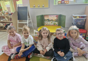 Klara, Ignaś, Oliwka, Antoś i Nadia siedzą na dywanie. Za dziećmi widać ustawiony Teatrzyk Kamishibai.