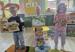 Tymek, Lucjan, Weronika i Ala pozują do zdjęcia trzymając w dłoniach ulubione książki.