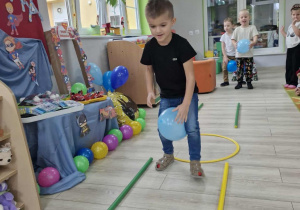 Staś idzie po torze z niebieskim balonem miedzy kolanami.