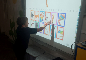 Marcel stoi przed tablicą multimedialną i dobiera instrumenty do pary.