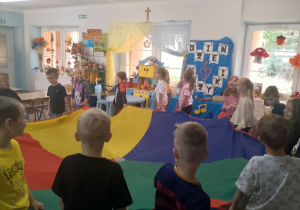 Dzieci idą po kole trzymając chustę animacyjną.