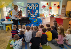 Pani stoi przed dziećmi i prezentuje przedszkolakom smyczek.