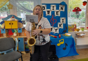 Pani gra na saksofonie, do którego zamocowała lirkę z nutami.