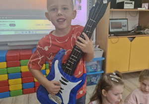 1.Lucjan stoi przed tablicą multimedialną i udaje że gra na gitarze elektrycznej