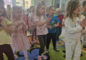 6.Dzieci stoją na dywanie i tańczą do piosenki wyświetlanej na tablicy multimedialnej