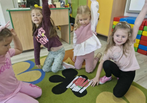 16.Klara, Oliwia, Ala i Ola siedzą na dywanie i trzymają rączki w górze na znak, że udało im się ułożyć obrazek jabłka z części
