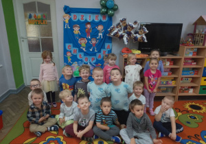 Grupa „Motylków” pozuje do wspólnego zdjęcia na tle dekoracji z napisem „dzień chłopaka”
