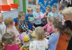 Dziewczynki z panią wręczają uśmiechniętym chłopcom prezenty