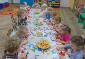 Cała grupa przy wspólnym stole z apetytem zjada deserki i babeczki