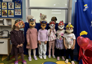 Dziewczynki z grupy pszczółek pozują do zdjęcia w maskach z psiego patrolu.