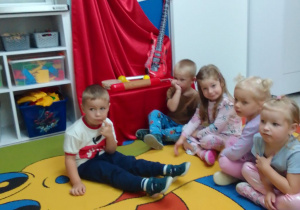 Pszczółki na dywanie, w tle dekoracja na tablicy.